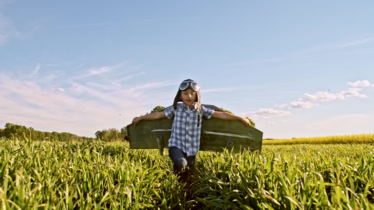 SLO MO Little boy in a jet pack costume running in a wheat field