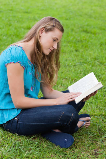 istock Serious young girl reading a book while sitting in a park 825254040
