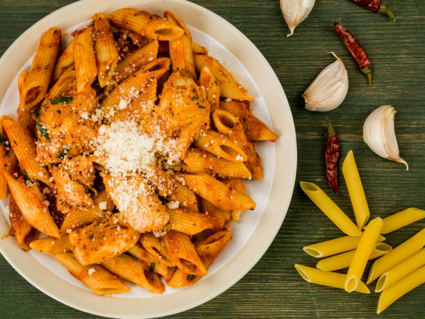 Italian Style Spicy Chicken Penne Pasta Arrabbiata Italian Style Spicy Chicken Penne Pasta Arrabbiata Against a Green Wooden Background chicken rigatoni stock pictures, royalty-free photos & images