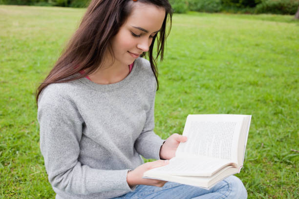 istock Young relaxed girl reading a book while sitting in a public garden 825291804