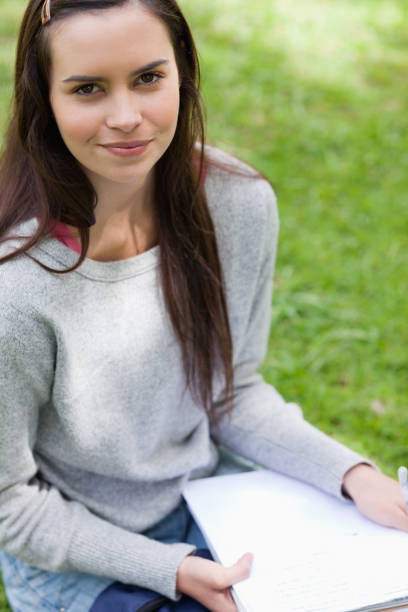istock Young calm girl sitting in a park while holding books 825291894