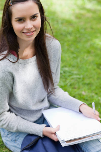 istock Smiling young girl sitting in a park while looking at the camera 825291920