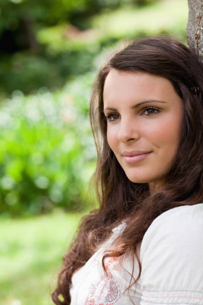 istock Peaceful woman leaning against a tree while looking towards away 825294546