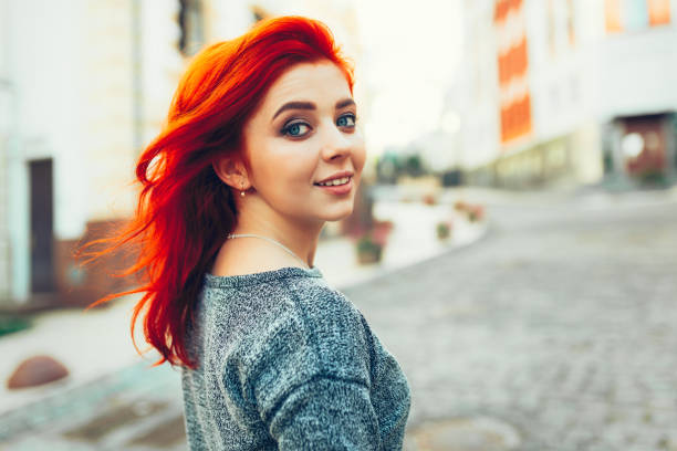 istock Startled young redhead woman looking back over her shoulder at the camera as she strolls down a deserted urban street 825295858