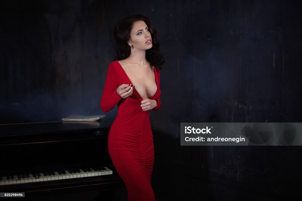 belle jeune femme attrayante en piano et robe rouge de soirée - Photo de Piano libre de droits