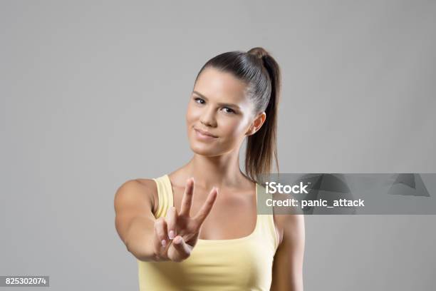 Gorgeous Sporty Young Female Portrait Showing Two Finger Peace Hand Sign Stock Photo - Download Image Now
