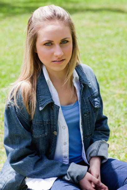 istock Young serious girl sitting on the grass while looking at the camera 825313074