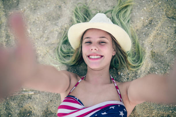Smiling Girl With Straw how Lying on Beach Sand and Taking Selfie