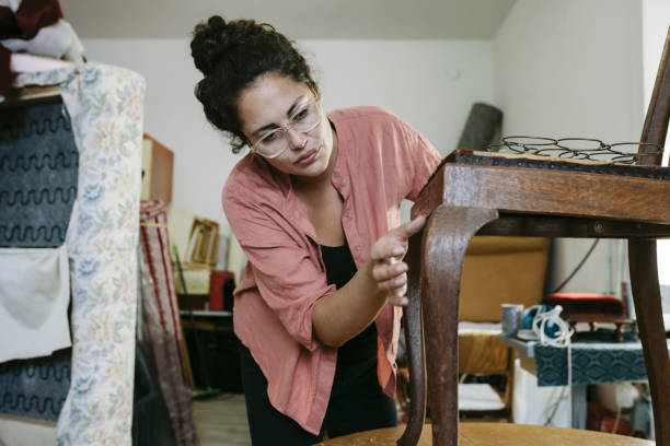 istock Craftswoman Inspecting Old Chair In Upholstery Workshop 825324116
