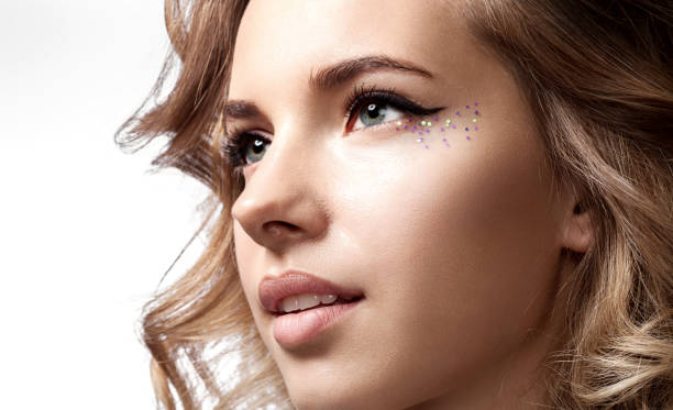 Close-up of a woman's face with a with a natural beauty and shiny  makeup  with sparkles Close-up of a woman's face with a with a natural beauty and shiny  makeup  with sparkles glitter makeup stock pictures, royalty-free photos & images