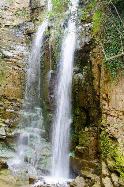 istock Large rain forest waterfall, sun beams, and mossy rocks 825325800