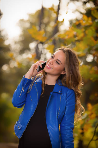 istock Young girl using cellphone in the park with autumn / fall colors. 825332692