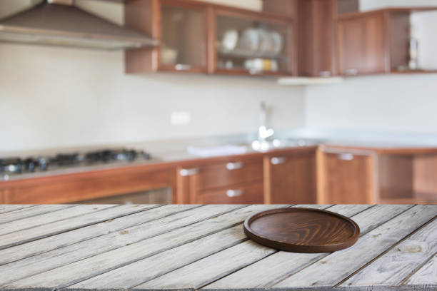 istock Blurred and abstract kitchen background. Empty wooden tabletop with tray and defocused modern kitchen for display or montage your products. 825336172