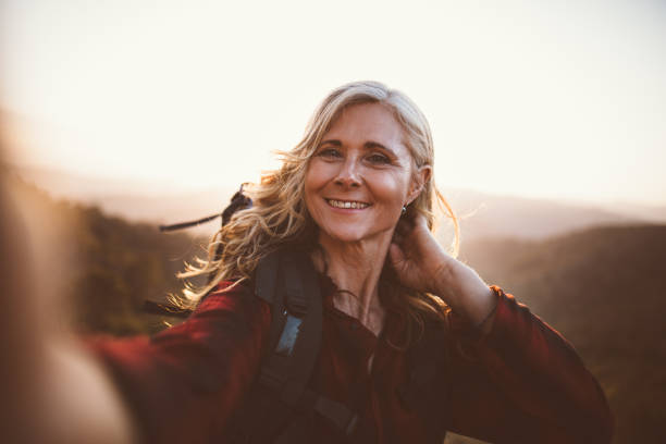 istock Senior woman hiker taking a selfie standing on mountain cliff 825337698