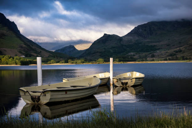istock Stunning dramatic stormy sky formations over breathtaking mountain lake landscape with rowing boats in foreground 825347768