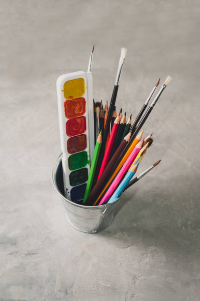 istock Drawing accessories - pencils, paints and brushes on a gray background 825352768
