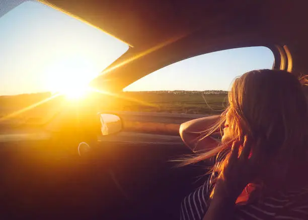 Photo of Young woman enjoying the car ride at sunset