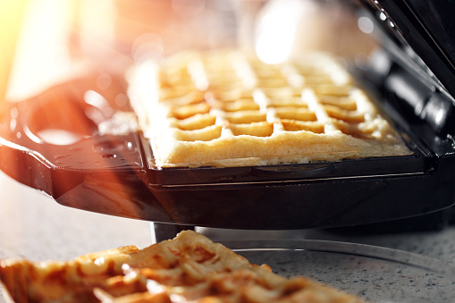 Freshly baked traditional Belgian waffles in iron waffle maker. family morning, prepare Breakfast