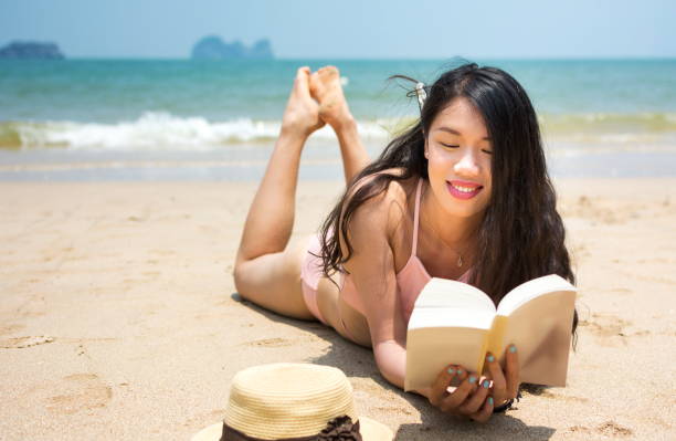 istock Girl reading book and sunbathing on the beach 825360304
