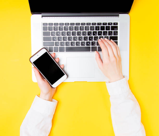 istock hand holding mobile phone and typing on laptop 825371658