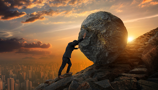 Hombre de negocios empujando una piedra grande hasta colina, pesadas tareas de la empresa y concepto de problemas. photo