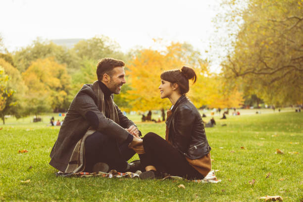 istock Couple sitting together in park and looking at each other 825390048