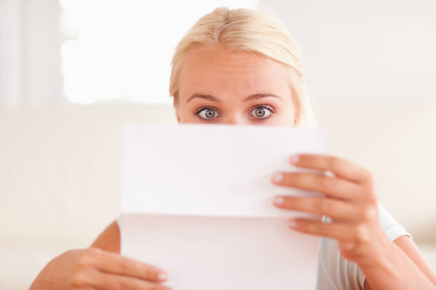 A girl in a coat carefully looking on the account received by mail.