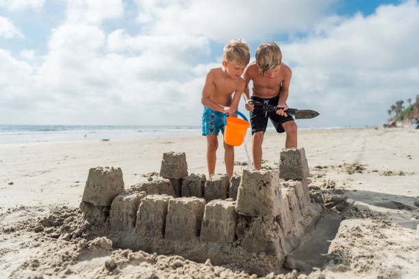 istock Brothers At The Beach Building A Sand Castle 825390716