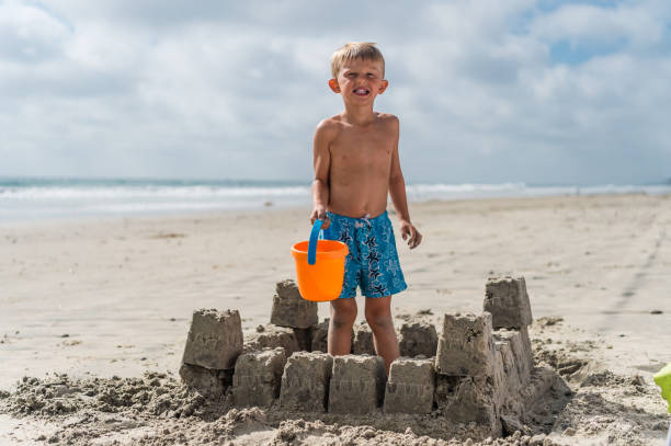 istock Blonde Boy At The Beach Building A Sand Castle 825390768