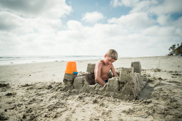 istock Blonde Boy At The Beach Building A Sand Castle 825391092