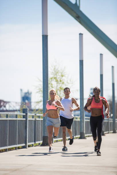 istock Co-Ed group running and exercising together outdoors in the sunshine 825391166
