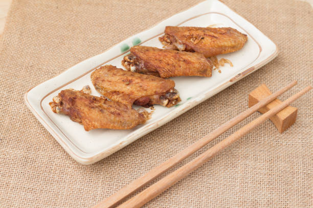 A plate of crispy shrimp paste fried chicken wings served with Thai chili sauce offers a delectable combination of crunchy chicken wings with a flavorful dipping sauce, providing a tantalizing culinary experience.