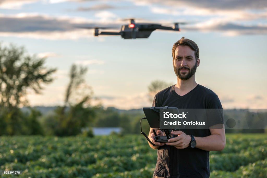 Man Pilot Using Drone Remote Controller at Sunset Man Pilot Using a Drone Remote Controller with a digital tablet at Sunset in a field. Drone Stock Photo