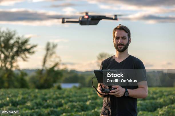 Man Pilot Using Drone Remote Controller At Sunset Stock Photo - Download Image Now - Drone, Farmer, People