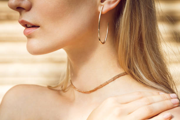 Detail of beautiful accessories Close-up of a beautiful young blonde woman's neck without a shirt with gold earrings and a tiny gold choker. half dressed girls pictures stock pictures, royalty-free photos & images