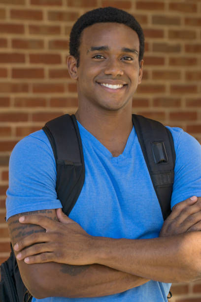 Smiling young black college student on campus carrying a backpack