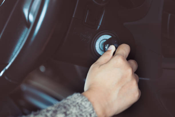 Woman hand put key into the ignition and starts the car engine stock photo