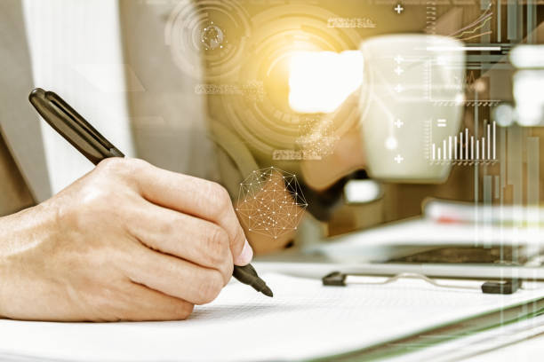 istock Using computer in office with a cup of coffee,Young woman working on a laptop computer while enjoying a cup of tea or coffee, close up side view of the notebook,business people,business background,business content and film effect. 825413788