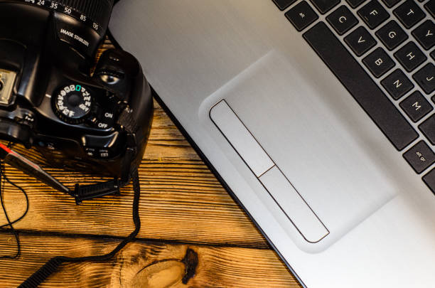 istock Modern DSLR camera and laptop on wooden table. Top view 825427852