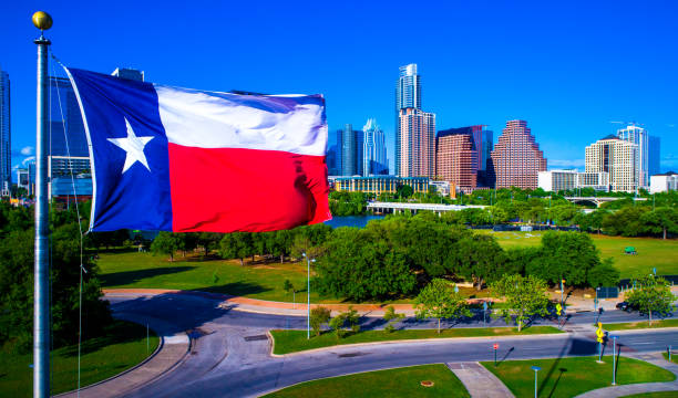 perfecta bandera de texas ondeando en el viento frente a día de cielo azul de austin texas horizonte urbano - lone star symbol fotografías e imágenes de stock