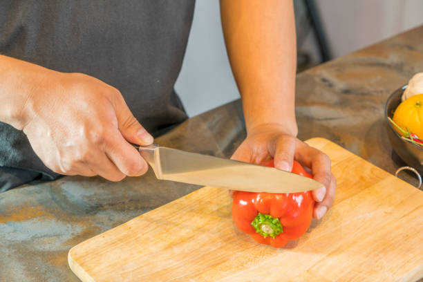 istock Chef cutting red bell pepper on wooden broad 825428344