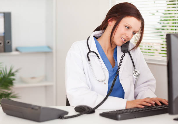 istock Female doctor telephoning and typing 825431772