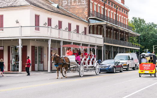 New Orleans, Louisiana, USA - June 25, 2017:  French Quarter, tourist landmark of New Orleans, Louisiana, USA. Entertainment for tourists is a riding horse-drawn carriage on the street in the French Quarter. Tour of the old streets of New Orleans