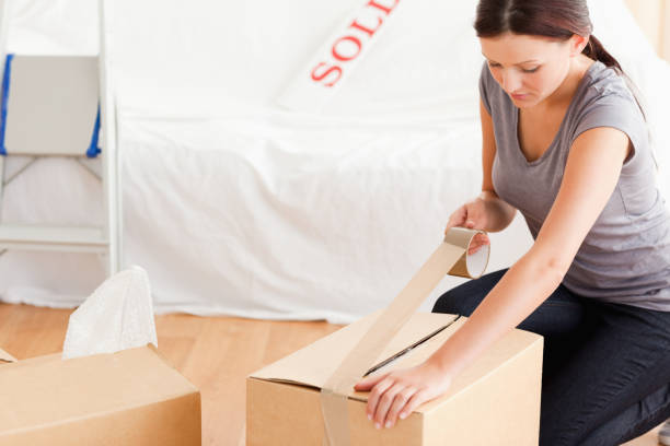istock A woman closing a cardboard with tape 825451182