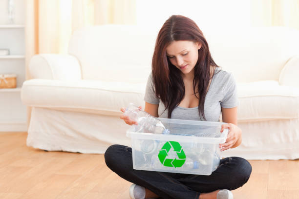 istock Cute woman putting bottles in a recycling box 825457918