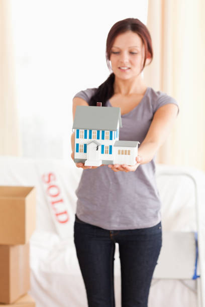 istock Redhaired woman showing a model house 825458042