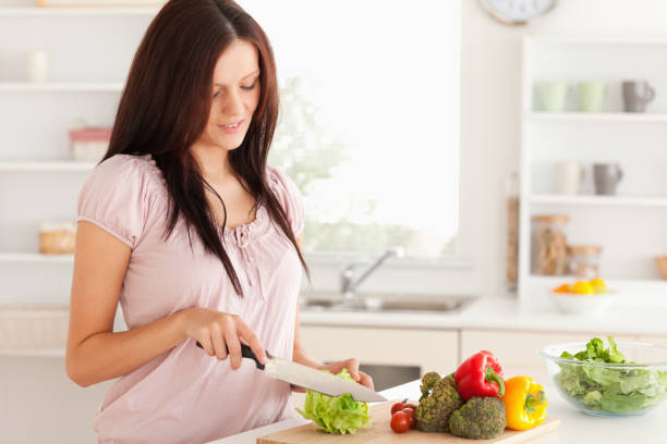 istock Beautiful woman cutting vegetables 825458268