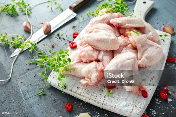 Fresh Raw Chicken Wings On A White Cutting Board With Thyme Chilli Salt Pepper Garlic Stock Photo - Download Image Now