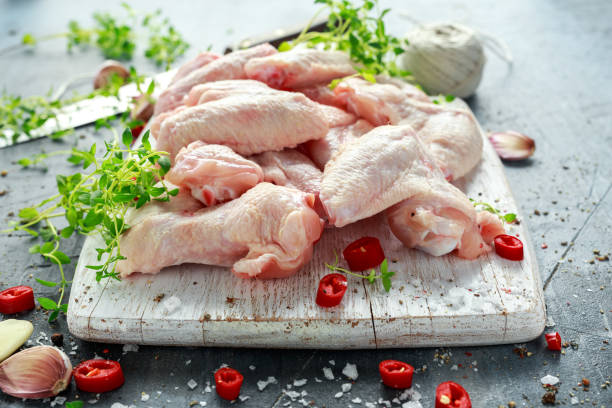 istock Fresh raw chicken wings on a white cutting board with thyme, chilli, salt, pepper, garlic 825461120