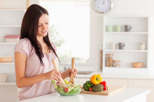 istock Cute woman mixing a salad 825465612